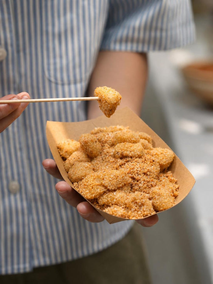 Soft muah chee coated in grated peanuts and sugar, picked up with a skewer